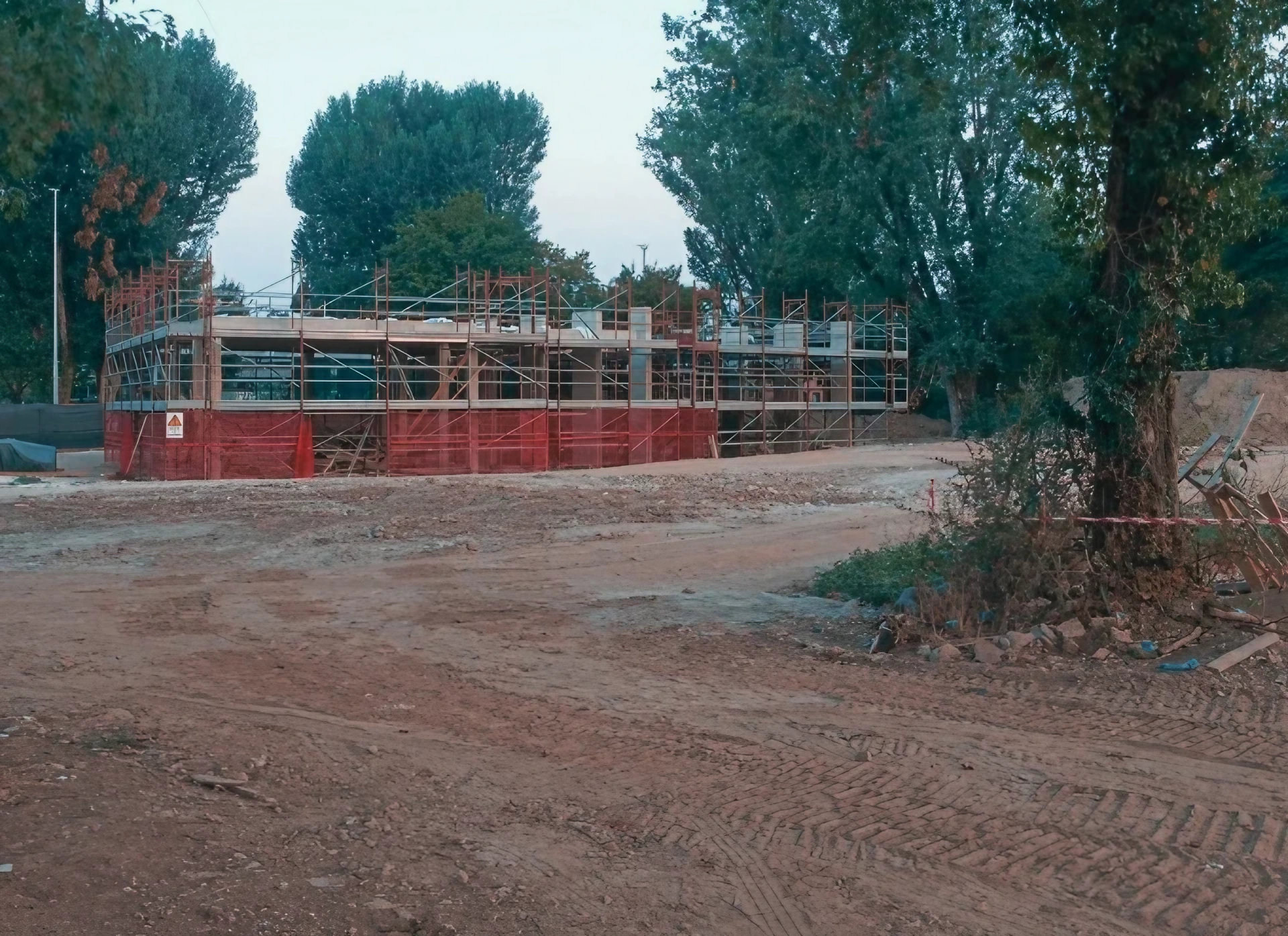 Cantiere edile con ponteggi e recinzioni di sicurezza, terreno smosso. Preparazione cantiere per demolizioni e tagli strutturali.