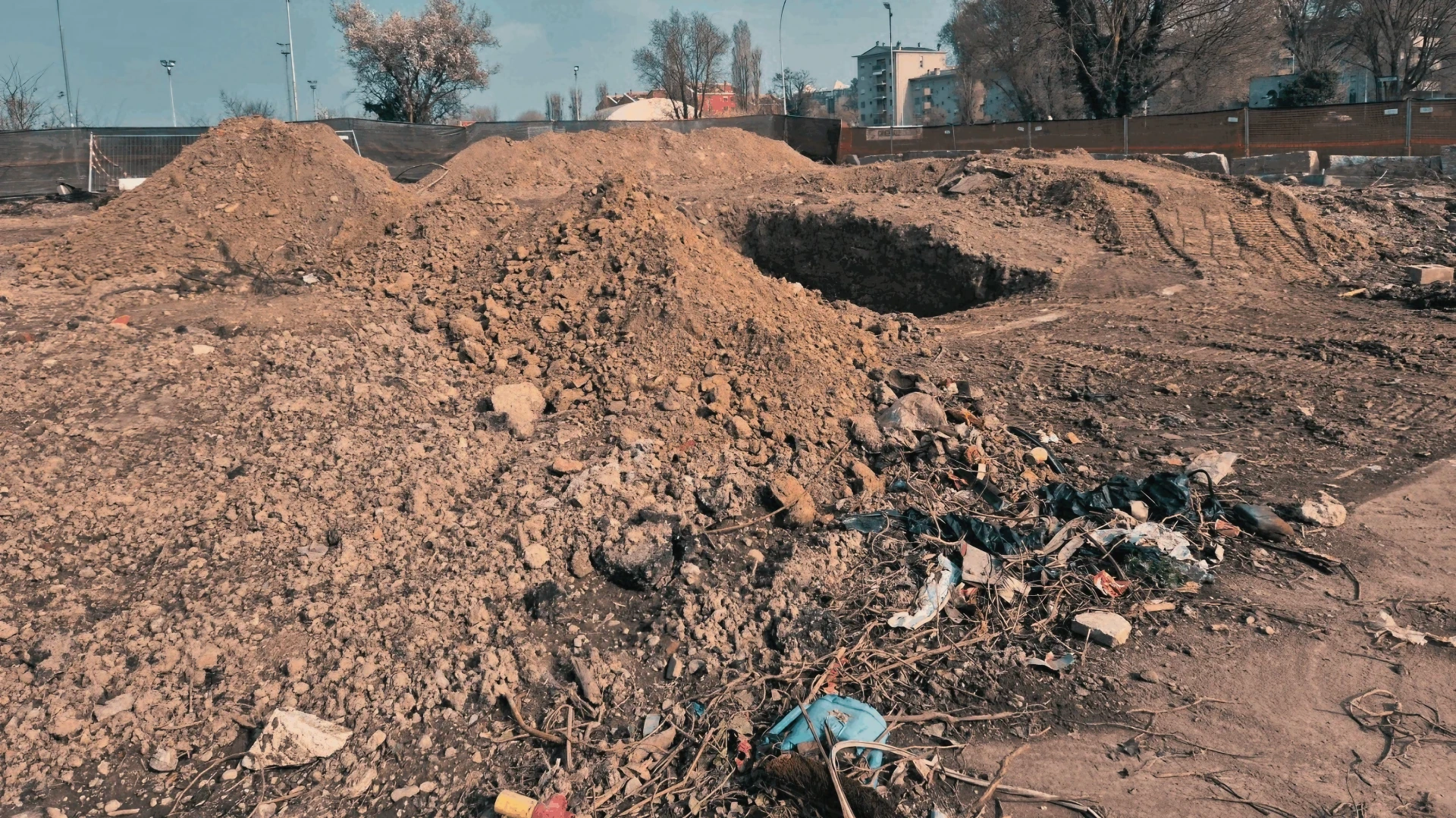 Cantiere con cumuli di terra e scavi per preparazione. Gestione materiali.
