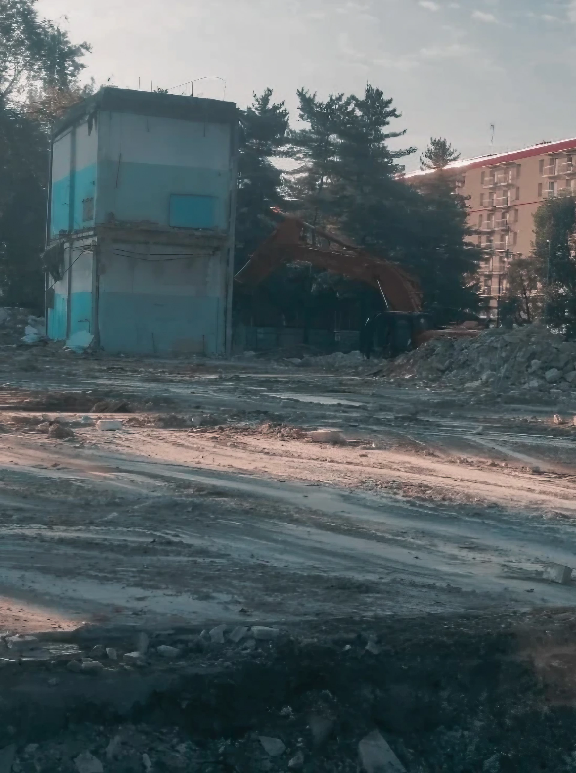 Cantiere di demolizione con edificio parzialmente abbattuto e escavatore, preparazione del sito.