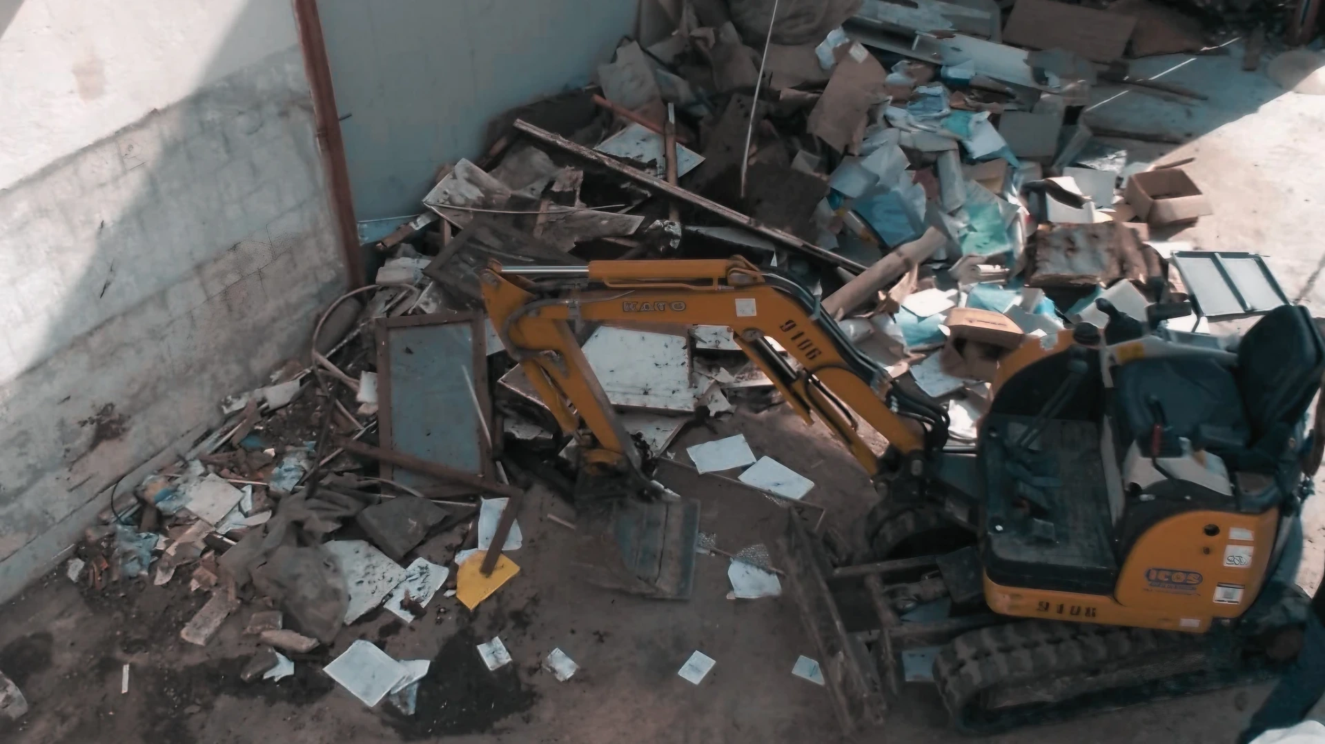 Mini escavatore giallo in cantiere per demolizioni e gestione detriti.