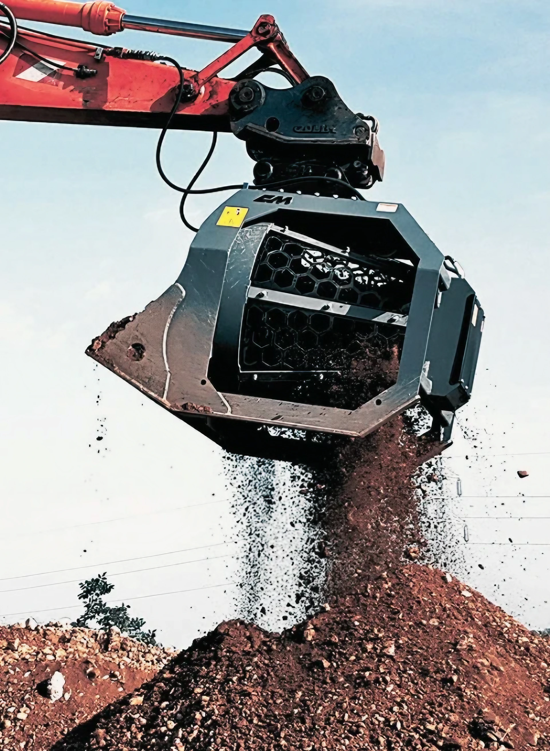 Escavatore con benna vagliante separa terra e detriti per preparazione cantiere.